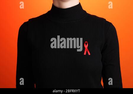 Woman with aids awareness red ribbon on orange background Stock Photo