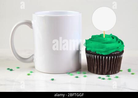 11 oz. Coffee Cup chilling next to a green frosted chocolate cupcake. Festive green sprinkles adorn this St. Patrick’s inspired mockup. Stock Photo