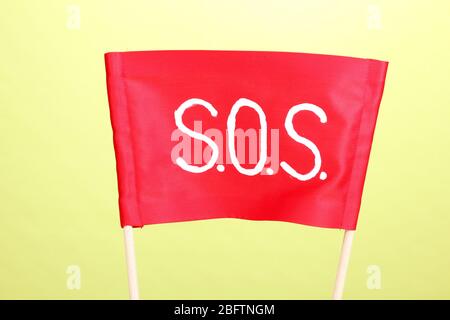 SOS signal written on red cloth on green background Stock Photo