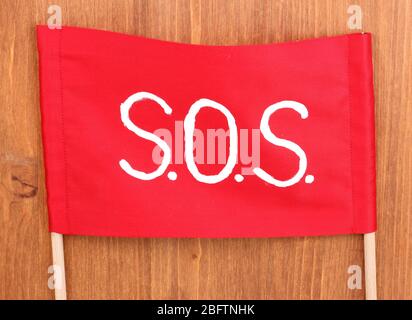 SOS signal written on red cloth on wooden background Stock Photo