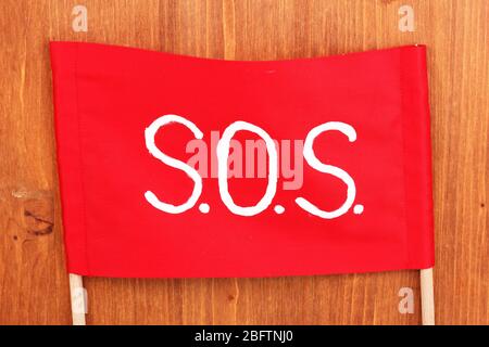 SOS signal written on red cloth on wooden background Stock Photo