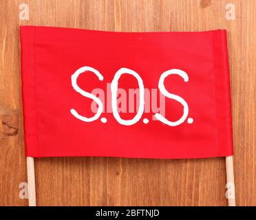 SOS signal written on red cloth on wooden background Stock Photo