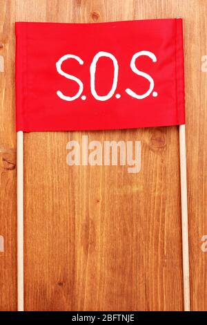 SOS signal written on red cloth on wooden background Stock Photo