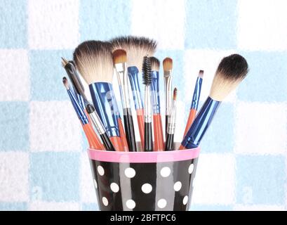 Makeup brushes in a black polka-dot cup on colorful background close-up Stock Photo