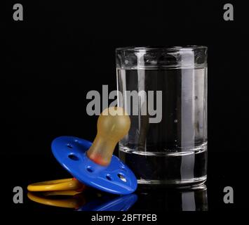 Baby dummy with alcoholic beverage isolated on black Stock Photo