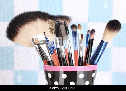 Makeup brushes in a black polka-dot cup on colorful background close-up Stock Photo