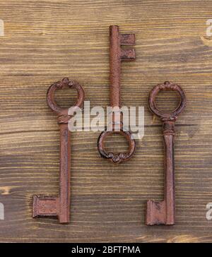 Three antique keys on wooden background Stock Photo