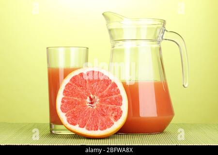 Grapefruit juice and grapefruit on bamboo mat on green background Stock Photo