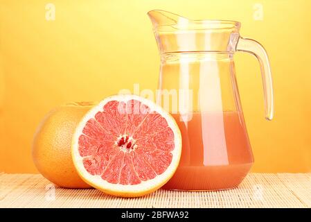 Grapefruit juice and grapefruit on bamboo mat on yellow background Stock Photo