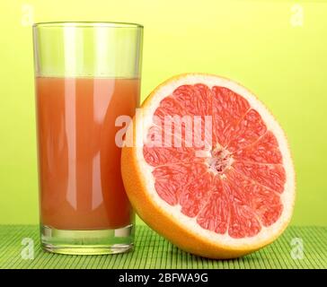 Grapefruit juice and grapefruit on bamboo mat on green background Stock Photo