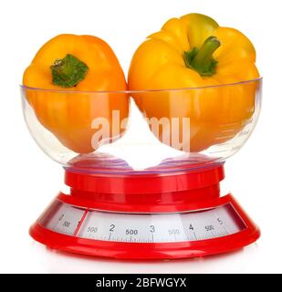 fresh orange peppers in a kitchen scales isolated on white Stock Photo