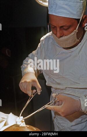 1993 - A Romanian doctor  begins to remove the packing from a Somali man who was wounded during fighting in Mogadishu.  The Somali was shot in the buttocks, sustaining damage to his small intestine, bladder, and bones in his upper leg.  This hospital is administered by the Romanians. Stock Photo