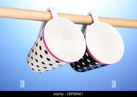 Nice cups hanging on stick on blue background Stock Photo