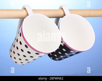 Nice cups hanging on stick on blue background Stock Photo