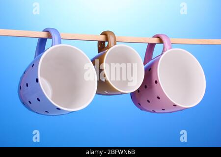 Nice cups hanging on stick on blue background Stock Photo