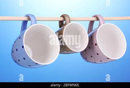Nice cups hanging on stick on blue background Stock Photo
