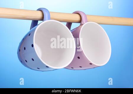 Nice cups hanging on stick on blue background Stock Photo