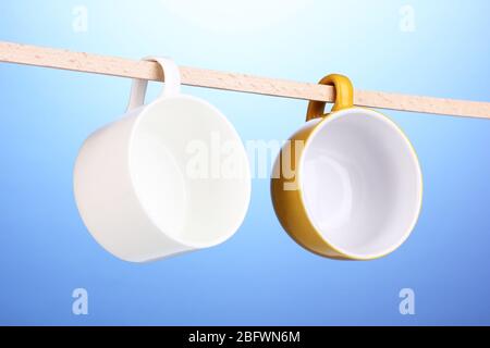Nice cups hanging on stick on blue background Stock Photo