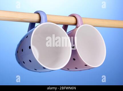 Nice cups hanging on stick on blue background Stock Photo