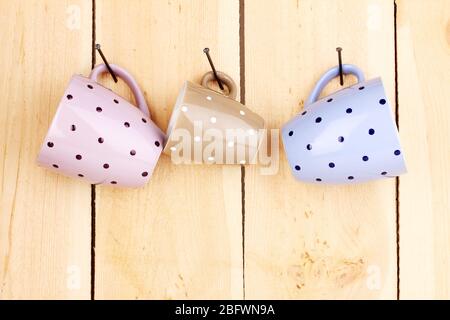 Nice cups hanging on nails on wooden background Stock Photo