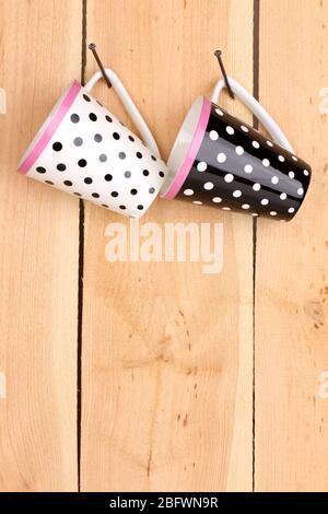 Nice cups hanging on nails on wooden background Stock Photo