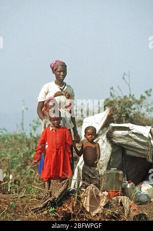 1994 - Rwandan refugee family of mother and children stand by a makeshift shelter, which along with what they carry, constitute all their worldly possessions.  They are in the Kibuma refugee camp near Goma Zaire after a civil war erupted in their country. Stock Photo