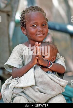A Somali girl holding an infant waits to be examined by a Navy corpsman.  Combat Service Support Detachment 15 (CSSD-15) is conducting a medical civic action program during the multinational relief effort Operation Restore Hope.