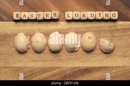Sweet Easter eggs as loading bar on a wooden board, wooden cubes with the inscription Easter loading Stock Photo