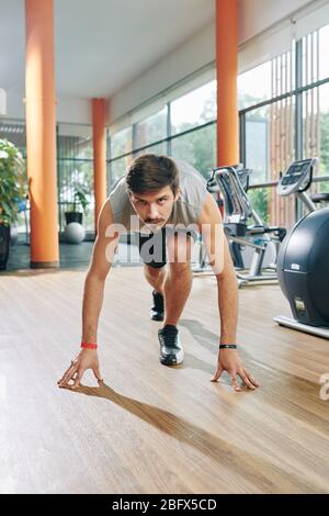 Handsome fit young man practicing starting position for running Stock Photo