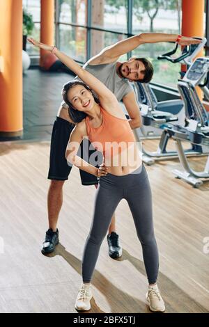 Smilng young multi-ethnic couple doing side bends and looking at camera Stock Photo
