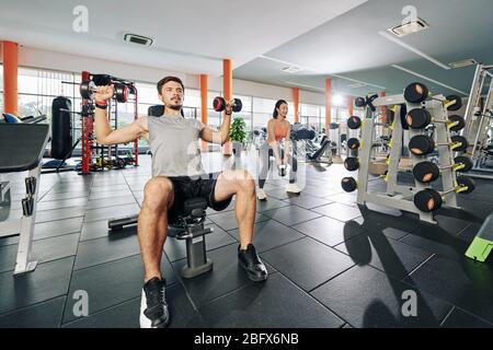 Young couple working out and and lifting weights in gym Stock Photo