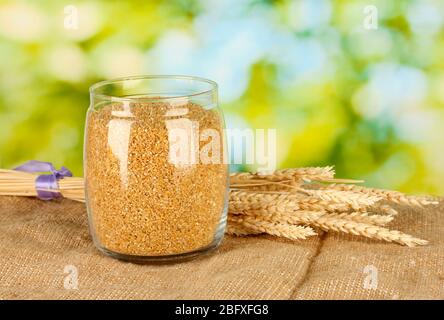 arnautka in glass jar with spikelets on green background close-up Stock Photo