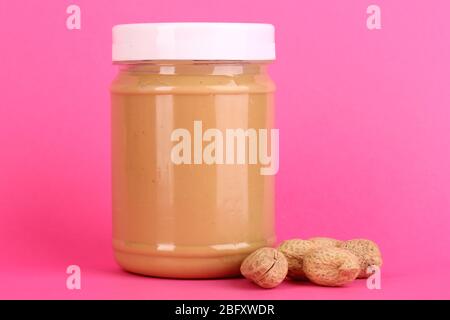 Delicious peanut butter in jar of peanut near on pink background Stock Photo