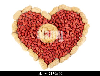 Delicious peanut butter in glass plate on picture of peanuts in form of heart isolated on white close-up Stock Photo