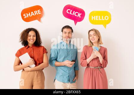 Portrait of positive modern multi-ethnic people interacting on social media, bright tags with social networking activity above them Stock Photo
