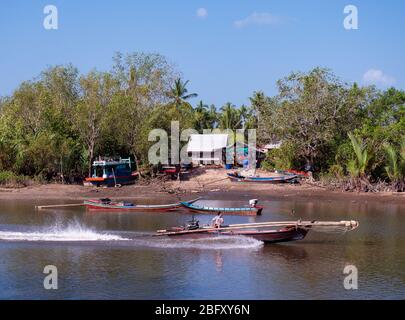 Small long tail fishing vessel on Mak Bang, Satun City, Satun in the south of Thailand. Boat building workshop in the background. Stock Photo