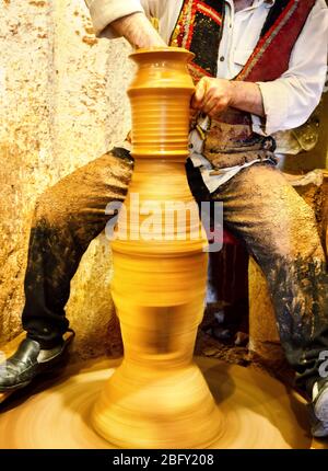 Potter makes a jug of raw clay on potter's wheel Stock Photo
