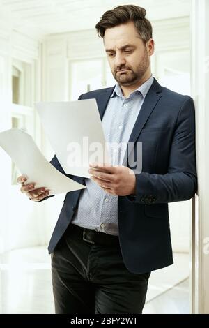 A businessman is reading. He is holding papers in his hands. Office, home office. Stock Photo