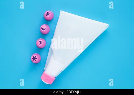 Cake decorating tools on blue background. White pastry bag with pink plastic nozzles for decoration baking Stock Photo