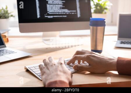 Close-up of unrecognizable programmer typing on keyboard while composing computer code Stock Photo