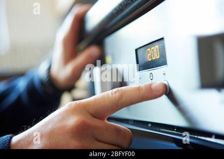 Close-up of a male hand starting a microwave oven for cooking food in kitchen at home, pushing a button. Stock Photo