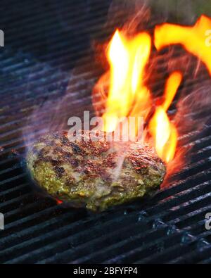 Burger barbeque being cooked on hot grill with smokey fire. Stock Photo