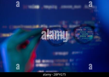 Close-up of male hand holding eyeglasses against computer code, defocused background around glasses Stock Photo