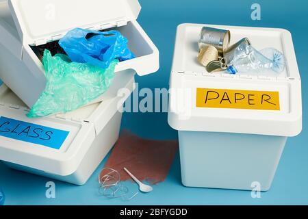 Close up of full trash bins for plastic and paper waste against blue background, sorting and recycling concept Stock Photo