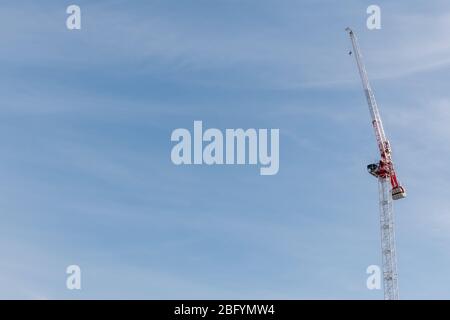 Red and white tower crane against a blue sky. Stock Photo