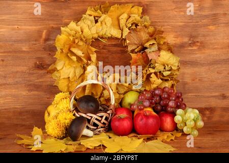 Autumnal composition with yellow leaves, apples and mushrooms on wooden background Stock Photo