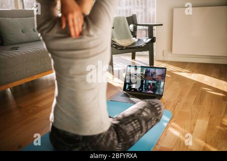 fitness coach teaching yoga online to group of people. Yoga trainer demonstrating yoga poses to students via video conference. Stock Photo