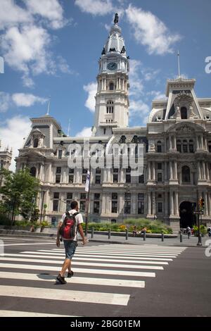 Vertical shot of a man crossing the street in front of the Town Hall, Philadelphia, Pennsylvania Stock Photo