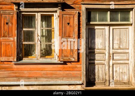 windows with open shutters and closed doors of an old wooden house on a sunny day Stock Photo