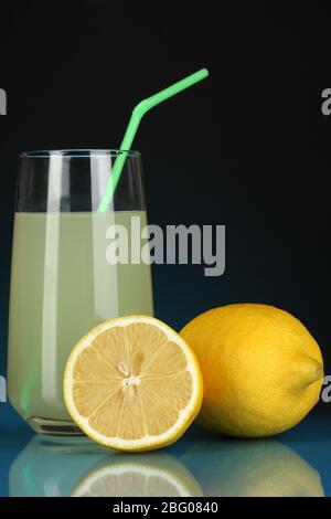 Delicious lemon juice in glass and lemons next to it on dark blue background Stock Photo